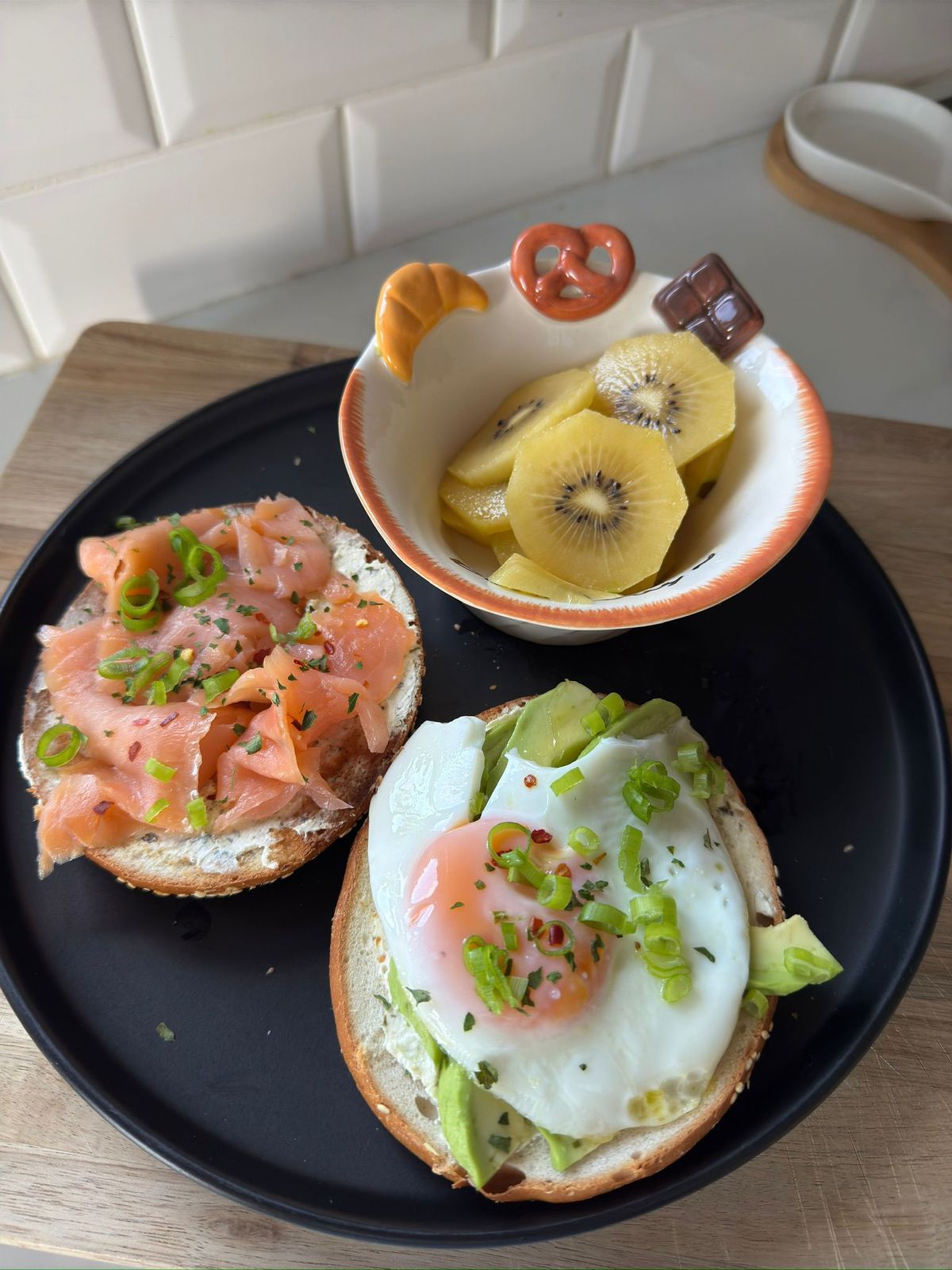 Prato com bagel, salmão, abacate, ovo e kiwi, exemplo de refeição equilibrada