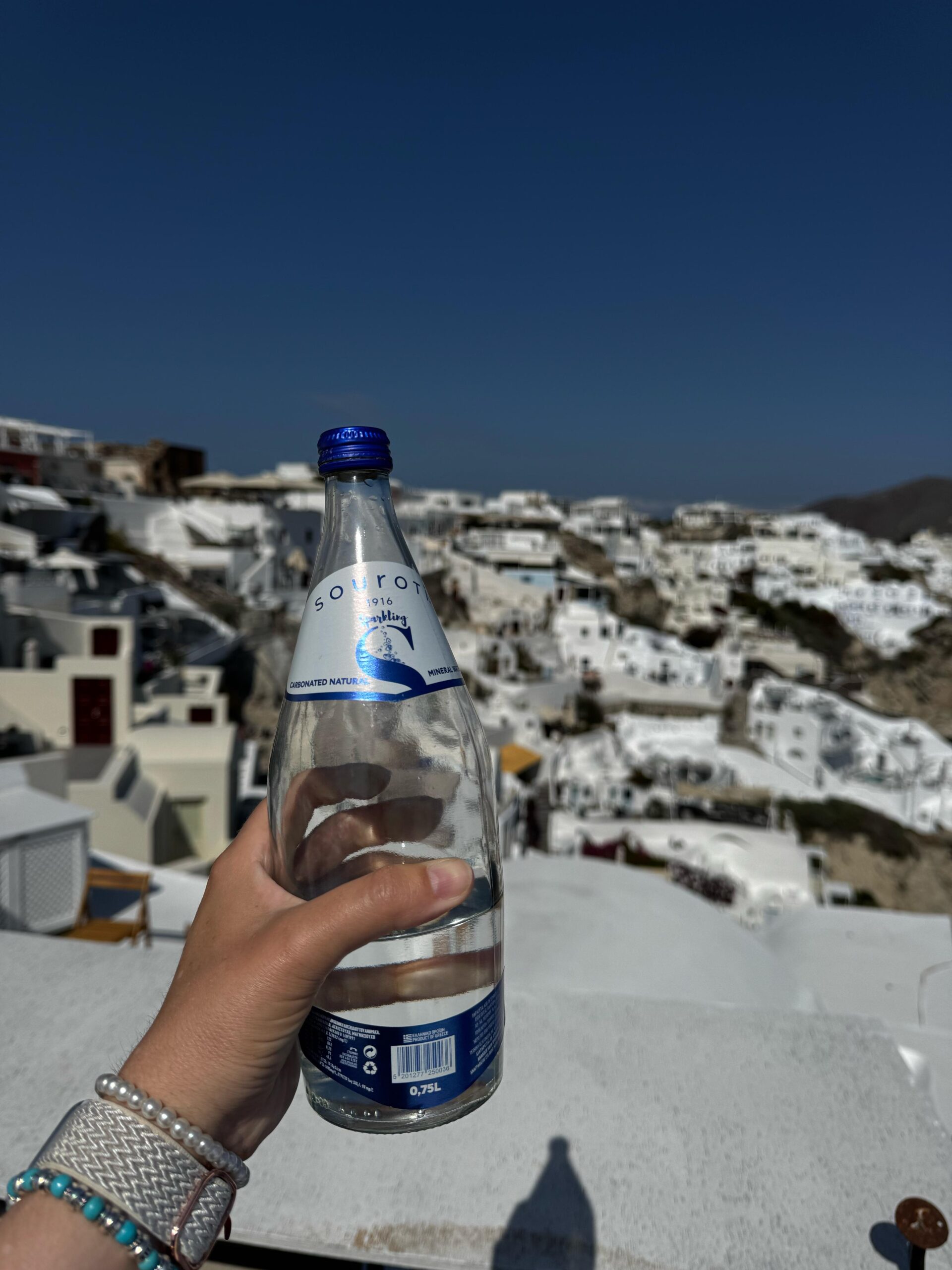 Pessoa segurando garrafa de água com vista europeia, representando a importância da hidratação para fortalecer a imunidade